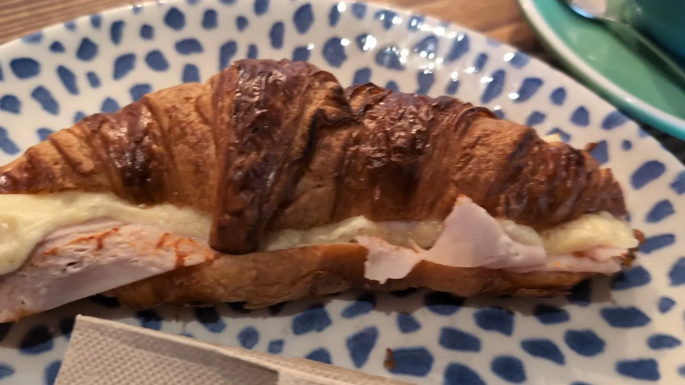 Croissant relleno de pavo sobre plato de lunares