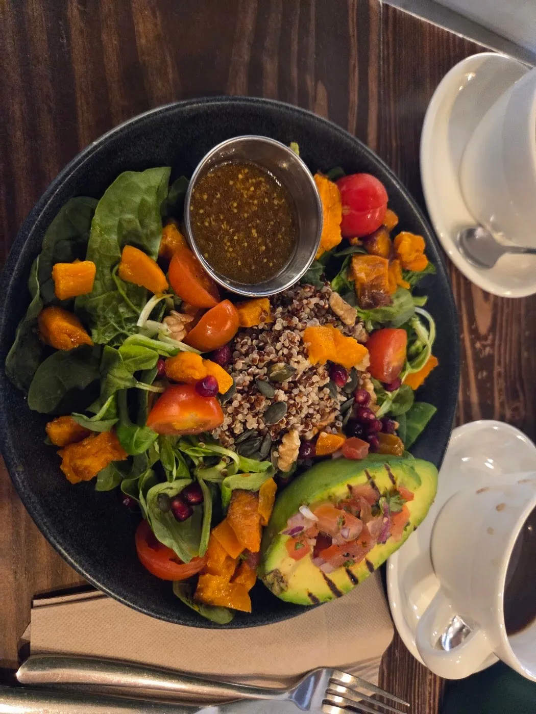 Bol de ensalada con quinoa, calabaza asada y medio aguacate